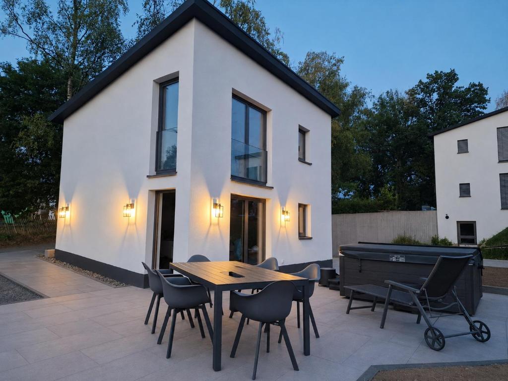 a white house with a wooden table and chairs at Eiflia- Im Ourtal in Burg-Reuland