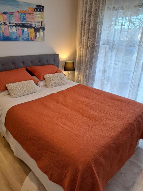 a bedroom with a large bed with an orange blanket at Kupe Boutique House with ensuite free wifi in Whitianga