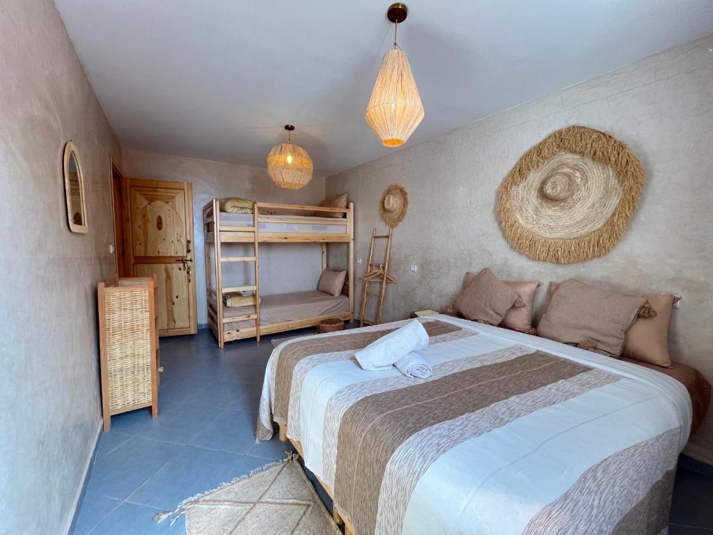 a bedroom with a large bed and a bunk bed at Little Palm Camp in Imsouane