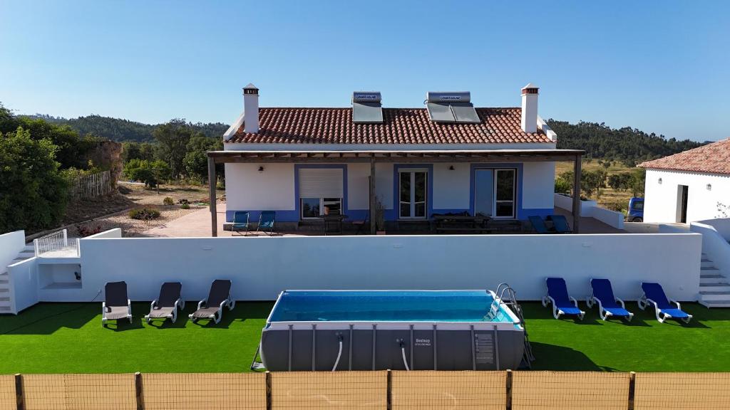 a white house with a swimming pool and chairs at Monte da Caniveta - Casa do Avô in São Luis