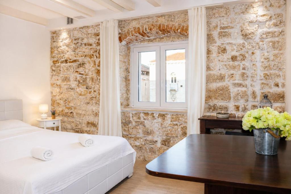 a bedroom with a bed and a table and a window at Trogir Square Apartment in Trogir