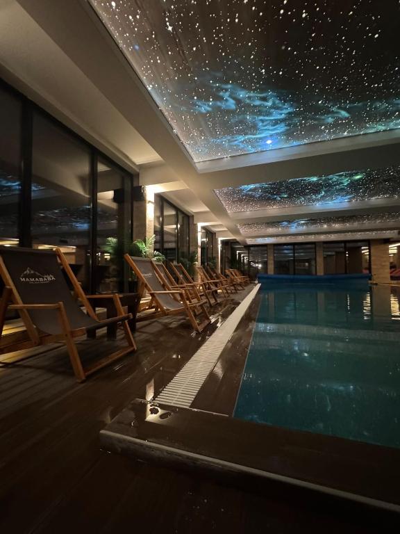 a swimming pool with chairs and a star ceiling at NLux Nest Milmari in Kopaonik