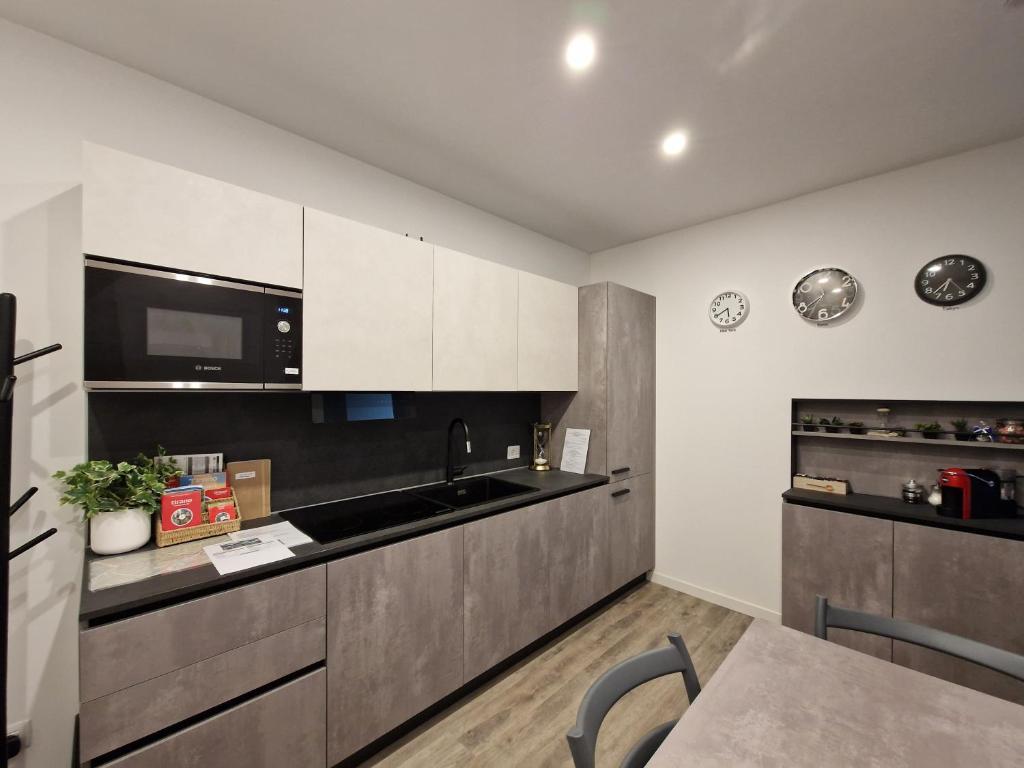 a kitchen with white cabinets and a sink and a microwave at A 2 min dal Trenino Rosso Monolocale CLESSIDRA1 in Tirano