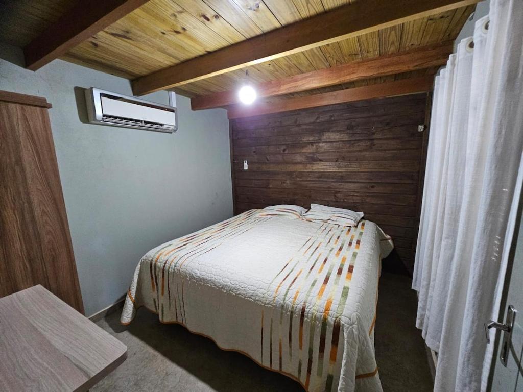 a bedroom with a bed and a wooden wall at Recanto Grande Lago in Massaranduba