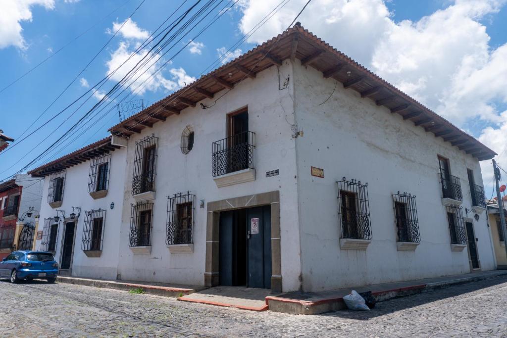 a white building with black windows on a street at House antigua Guatemala in Antigua Guatemala