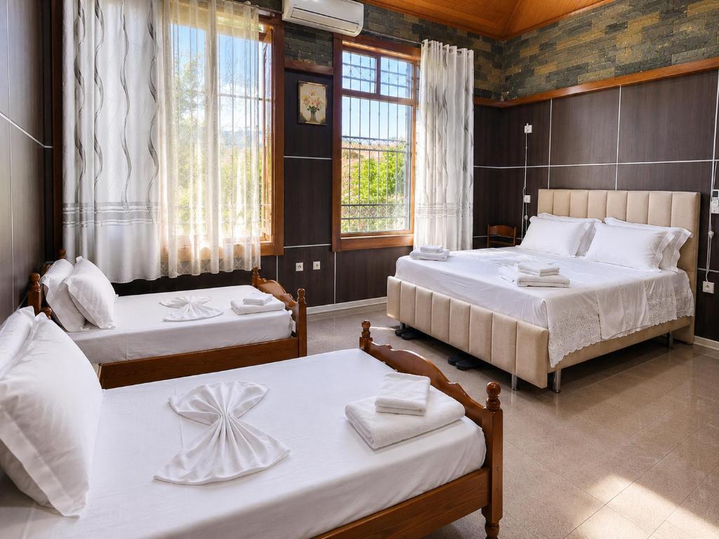 a bedroom with two beds and two windows at Guest House Univers in Berat