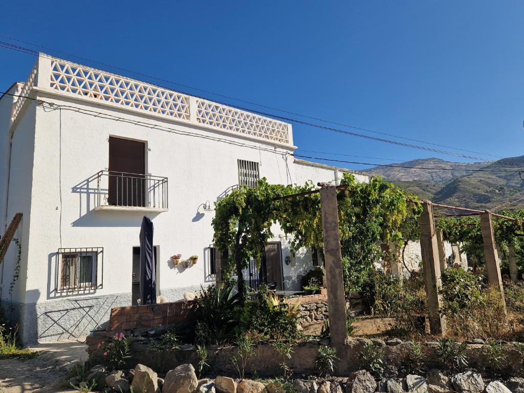 a white house with a balcony and a fence at B&B Cortijo Nunca Pense in Órgiva