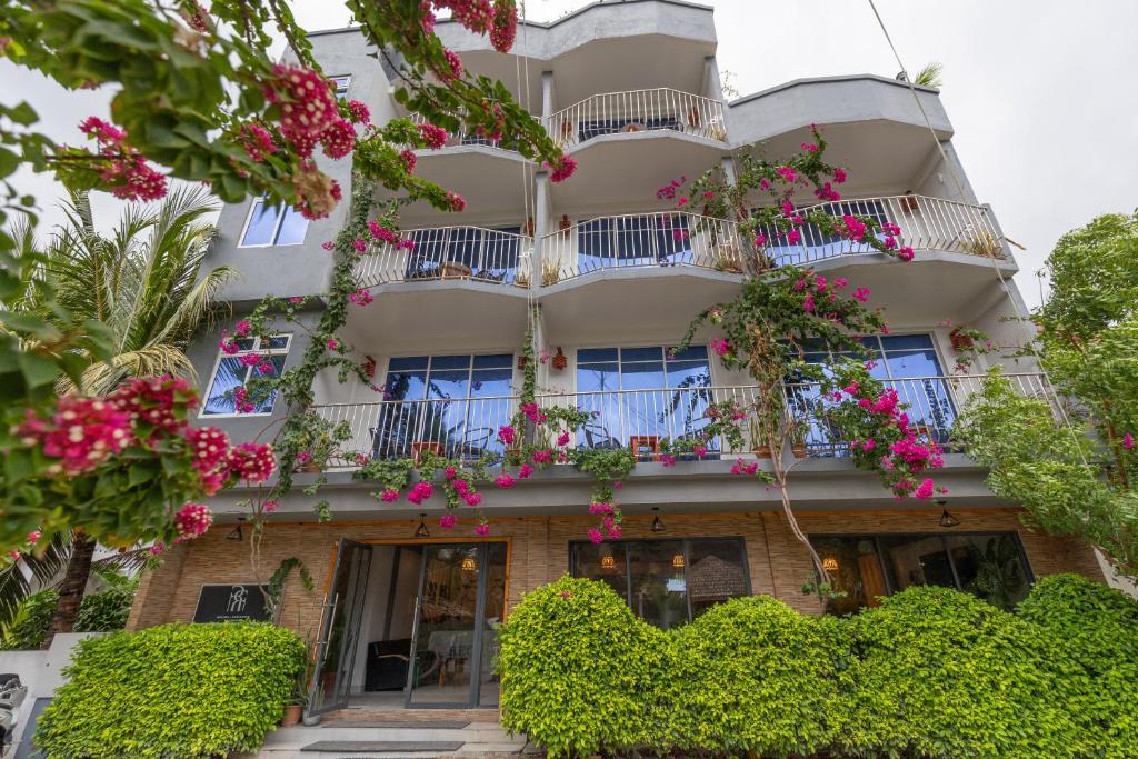 a building with pink flowers in front of it at Rihiveli Residence Thoddoo in Thoddoo