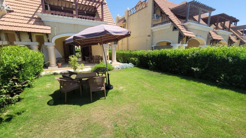 a patio with a table and an umbrella in a yard at Villa Marsilea in Dawwār Muḩammad Abū Shanab
