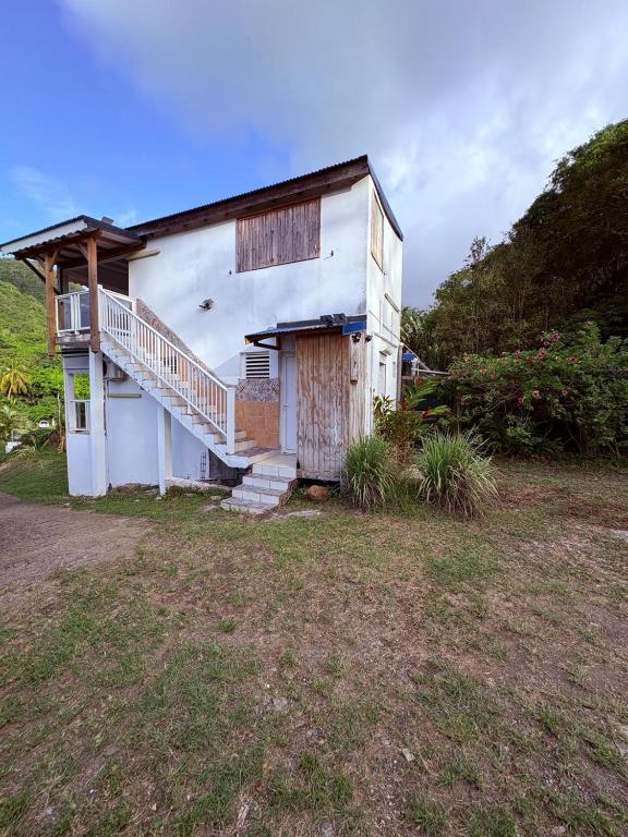 a white house with a porch and a staircase at Studio Arawak in Deshaies