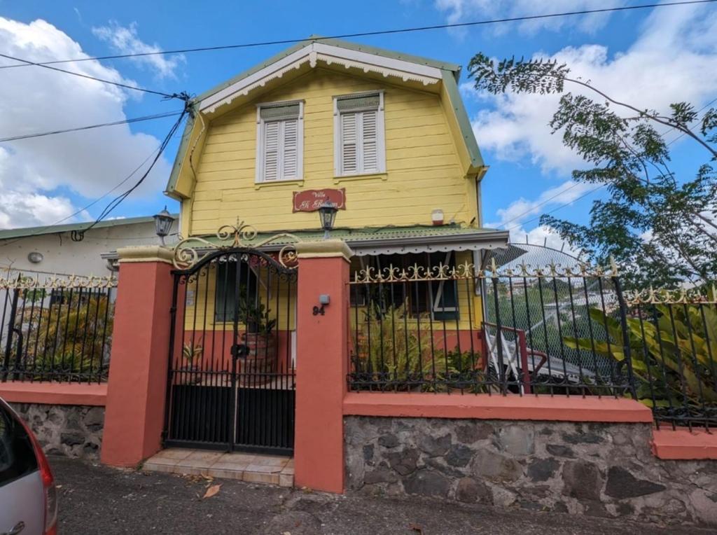 a yellow house with a fence in front of it at Villa Ti Balcon avec jacuzzi in Fort-de-France