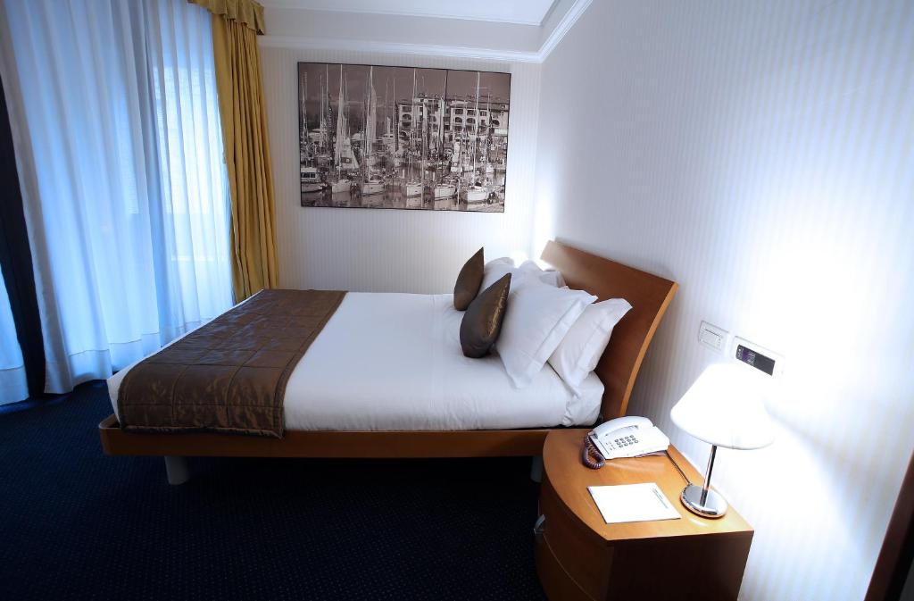 a hotel room with a bed and a table with a phone at Hotel San Rocco in Muggia