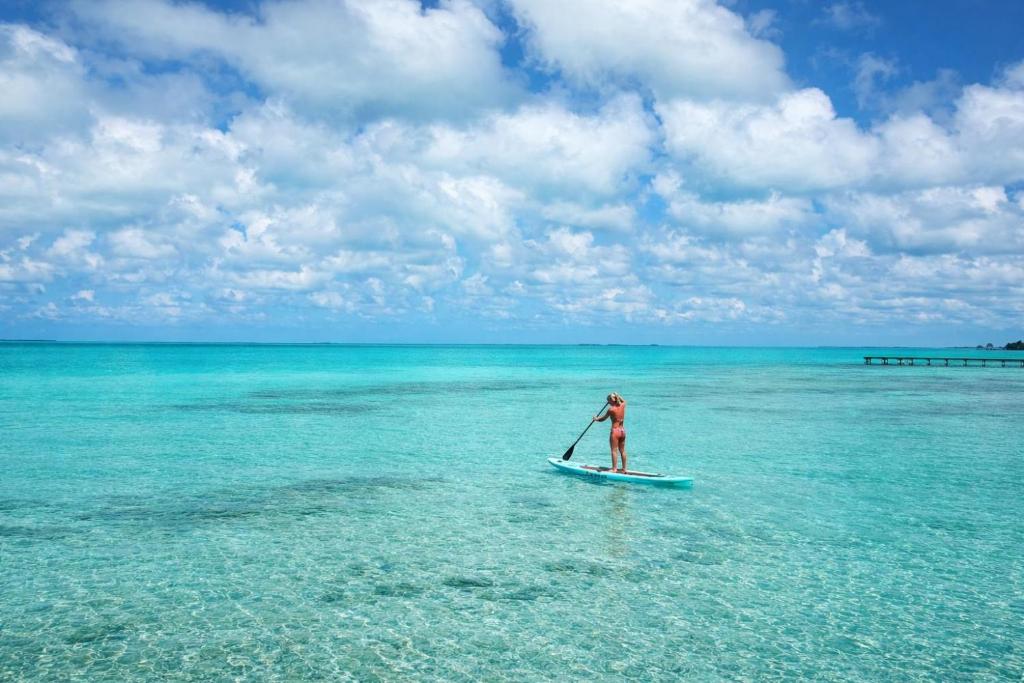 a woman standing on a paddle board in the ocean at Casa Nova Cabanas in San Pedro