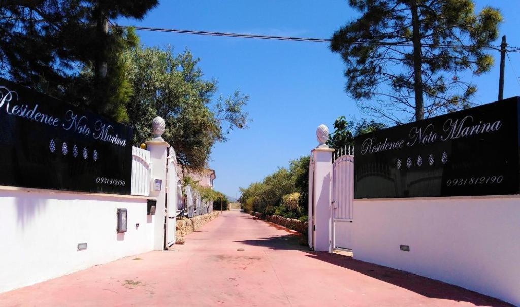 a street with white fences and trees on the side at Hotel Residence Noto Marina Relais in Calabernardo