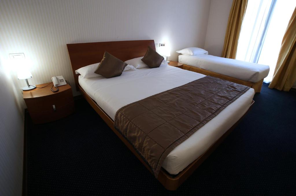 a hotel room with two beds and two lamps at Hotel San Rocco in Muggia