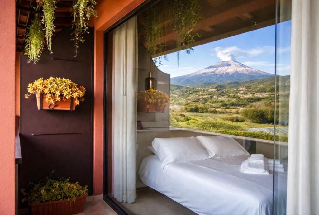 a bed in a room with a view of a mountain at Elgio' Design Retreat with Etna View Taormina in Taormina