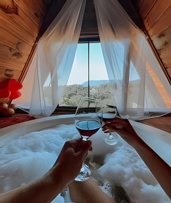 a person holding a glass of wine in a bath tub at Imperatriz Cabanas (Chalé 2 com piscina e hidro) in Santo Amaro da Imperatriz