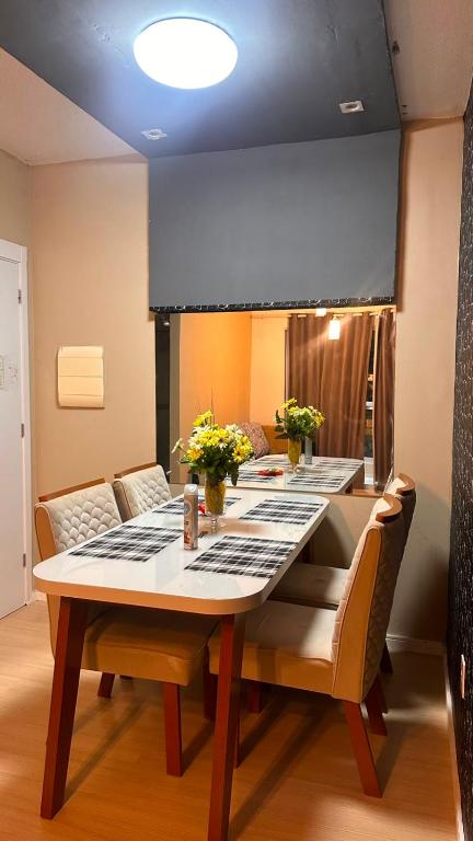 a dining room table and chairs with flowers on it at Aprt com ar varada conjugada,piscina in Aracaju