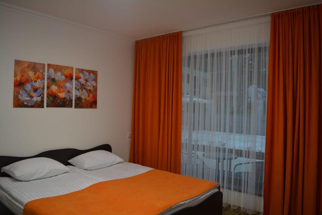 a bedroom with a bed and a window with orange curtains at Aaa in Stepʼanavan