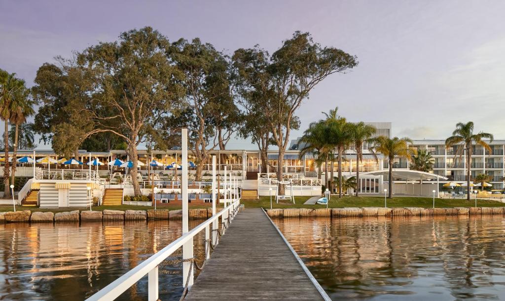 a dock in a marina with a hotel in the background at The Beachcomber Hotel & Resort in Toukley