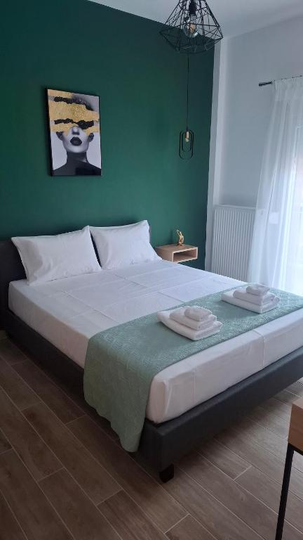 a bedroom with a large bed with a green wall at Luxury Green Apartment in Serres