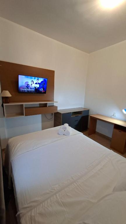 a hotel room with a bed and a flat screen tv at Studio Executivo Completo com Garagem , Ar e Wi-fi in Parauapebas