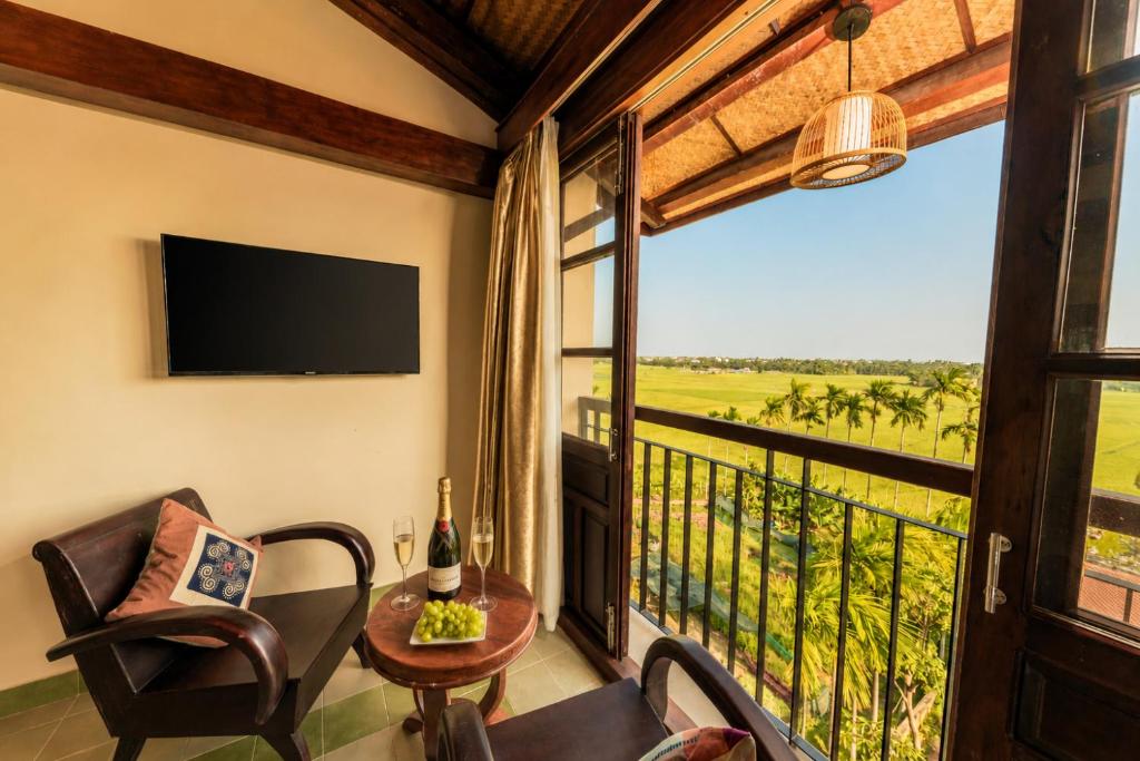 a room with a balcony with a tv and a chair and a table at Sola Hoi An in Thanh Ðông (1)