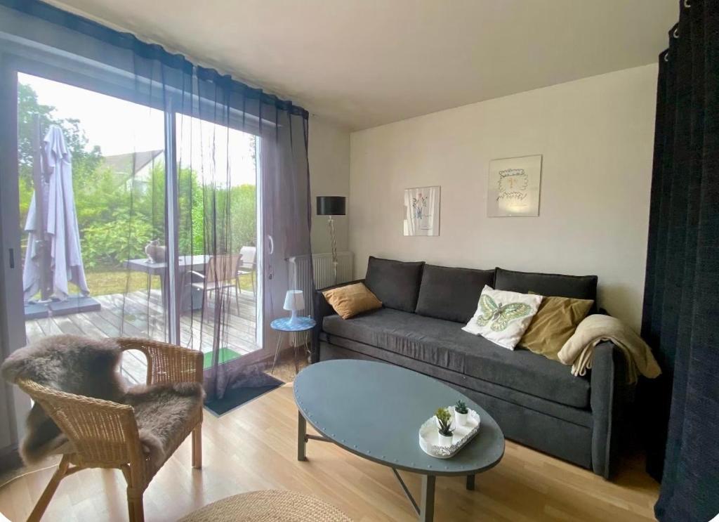 a living room with a couch and a table at Independent studio - Cicé Blossac Golf in Bruz
