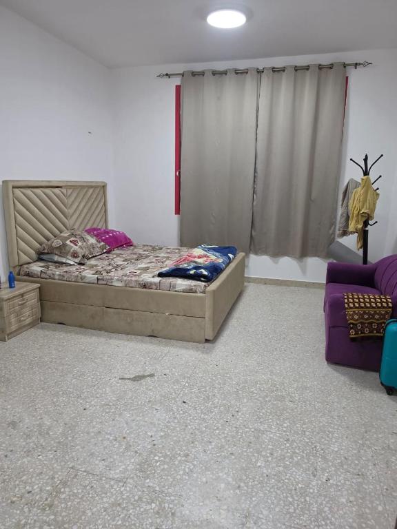 a bedroom with a bed and a purple couch at EZ Homes in Abu Dhabi