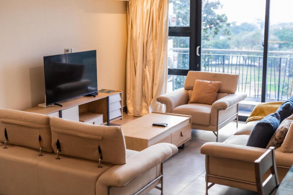 a living room with couches and a flat screen tv at Beaufort Ridge - Skysuites in Accra