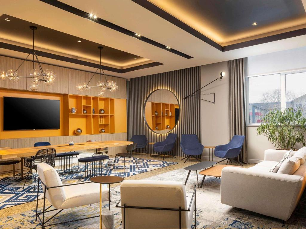 a living room with a table and chairs and a tv at Mercure Sibiu Airport in Sibiu