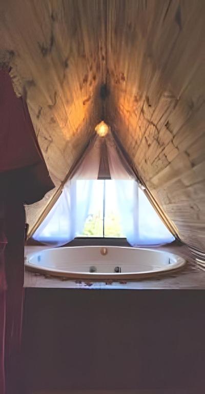 a window in a ceiling with a tub in a room at Imperatriz Cabanas (Chalé 1 com hidromassagem) in Santo Amaro da Imperatriz