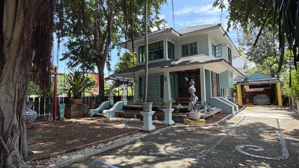 a green house with a statue in front of it at Cozy two-storey home in Ban Lam Praya Phai Rua