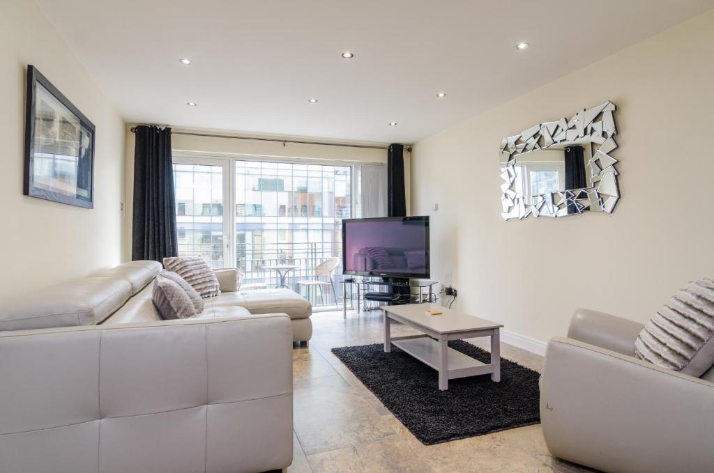 a living room with white furniture and a tv at Central City Apartment - Free Parking in Belfast