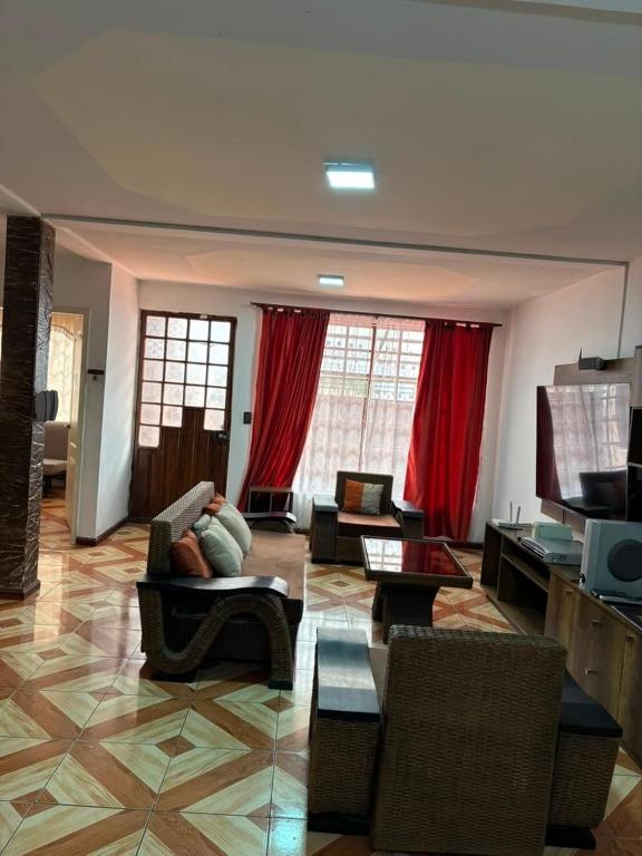 a living room with couches and chairs and red curtains at Casa de 3 pisos con área de gym y entretenimiento 4 habitaciones para hasta 8 personas in Cuenca