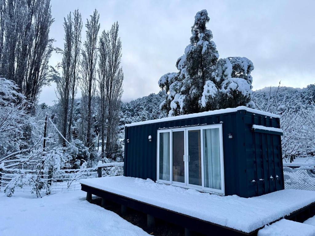 a cabin in the snow in front of a tree at El Refugio Container in Futaleufú
