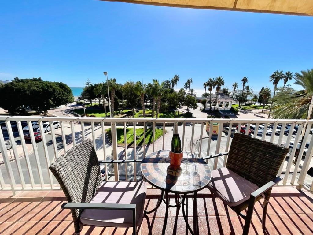 a table and chairs on a balcony with a bottle of wine at Apartamento El Nido in Torre del Mar