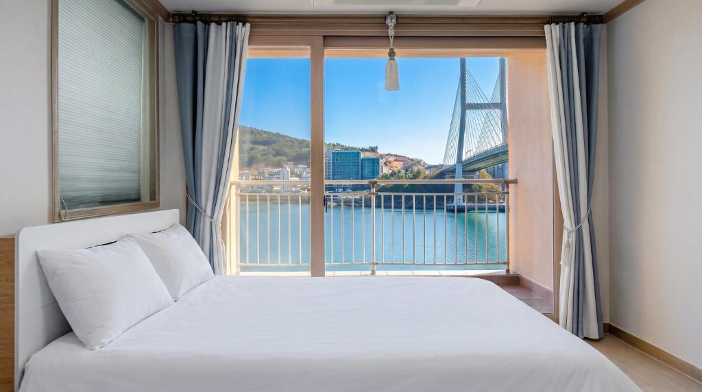 a bed in a room with a large window at Yeosu Turtleship Pension in Yeosu