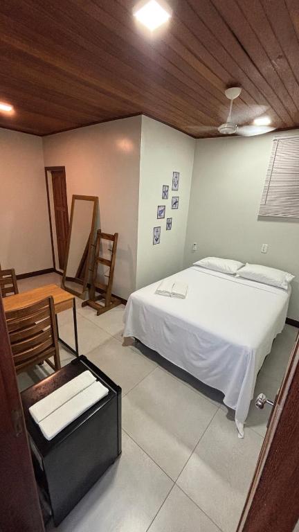 a bedroom with a white bed and a wooden ceiling at Suítes Aymoré in Itacaré