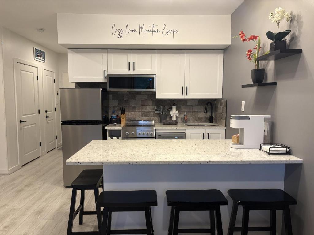 a kitchen with white cabinets and a counter with stools at Loon Resort Condo-AC, Pool, Hot Tub and Views in Lincoln