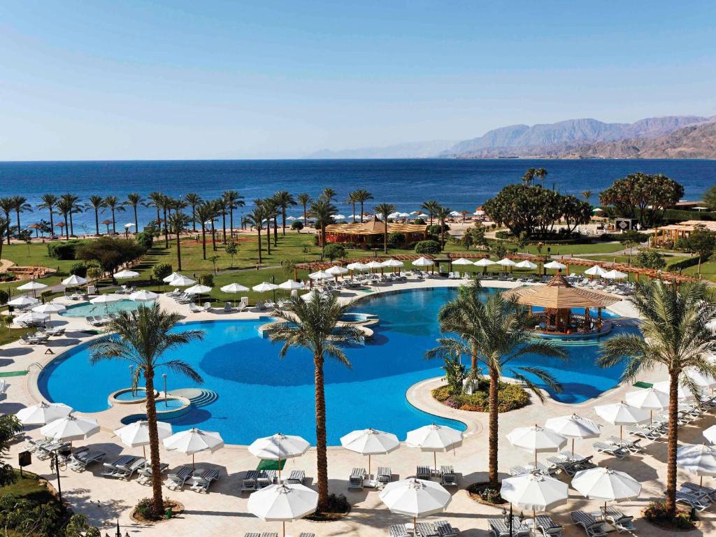 a view of a resort with a pool and palm trees at Movenpick Resort Taba in Taba
