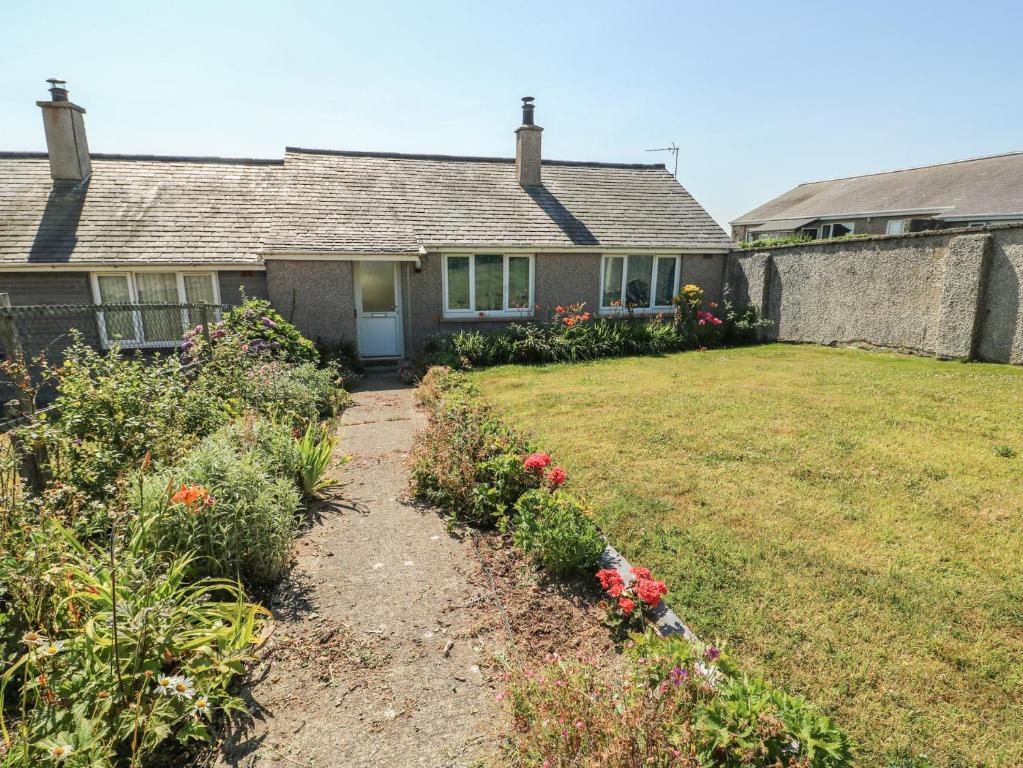 a house with a yard with flowers in front of it at 7 Bro Branwen in Aberffraw
