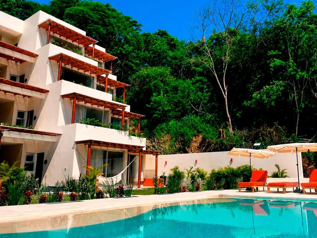 a hotel with a swimming pool in front of a building at Mabay in Zihuatanejo