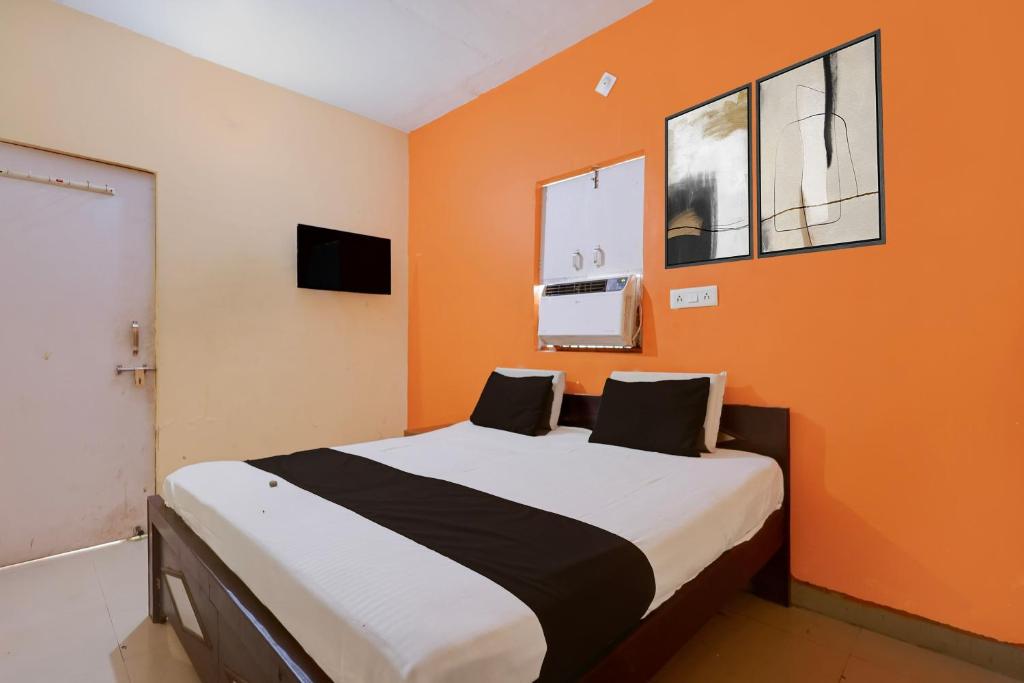 a bedroom with a bed with an orange wall at Hotel O Royal Inn Hotel in Hāpur