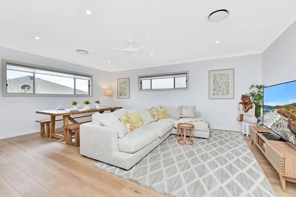 a living room with a couch and a tv at Finns at Caves Beach Resort in Caves Beach