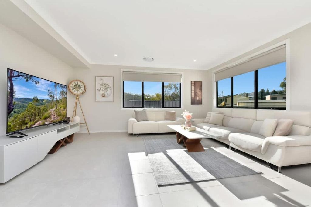 a living room with white furniture and large windows at Mount View Escape at Millfield in Millfield