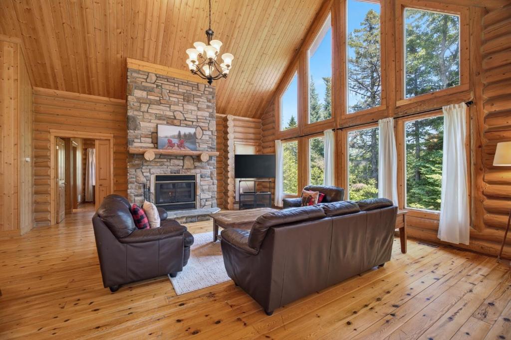 a living room with leather furniture and a stone fireplace at Fiddler Lake Resort - Deer 30 in Mille-Isles