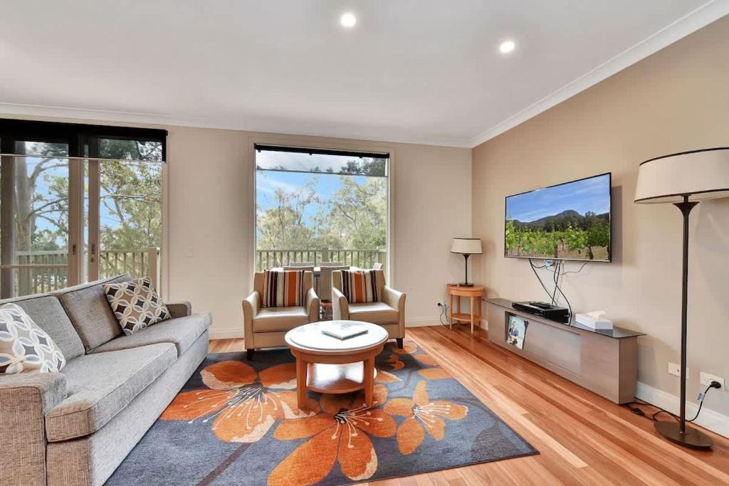 a living room with a couch and a tv at Villa 2br Pinot Nois Villa in Pokolbin