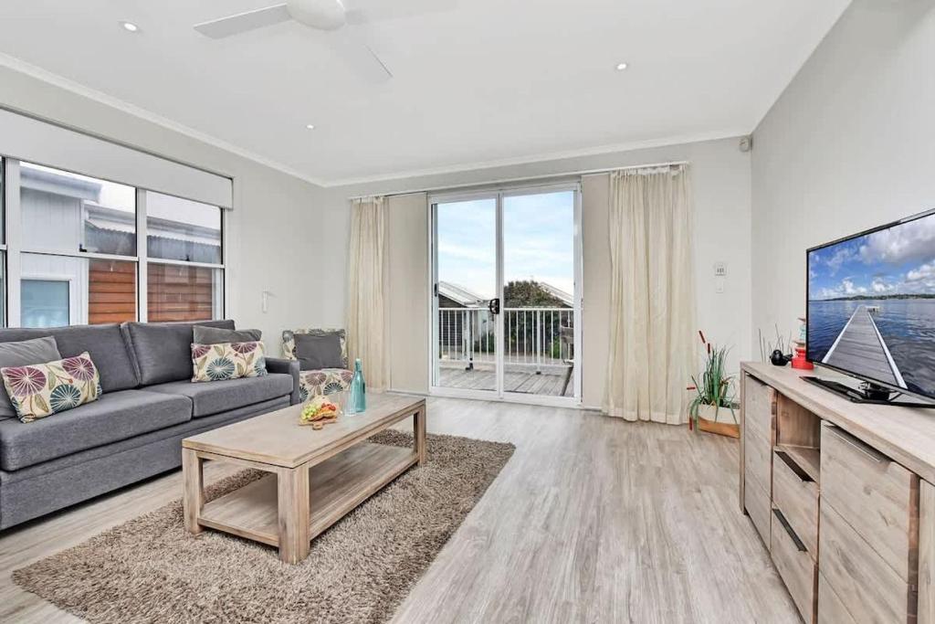 a living room with a couch and a tv at Beach Escape at Caves Beach Villas in Caves Beach