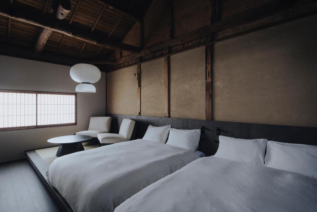 a bedroom with two beds and a table and chairs at 纏matoi in Maizuru